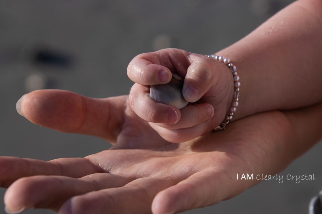 child holding a rock on a person's hand