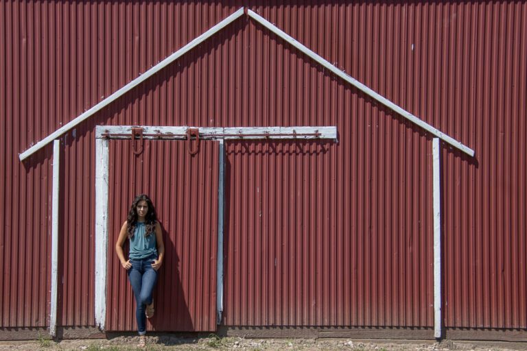 woman standing at red barn