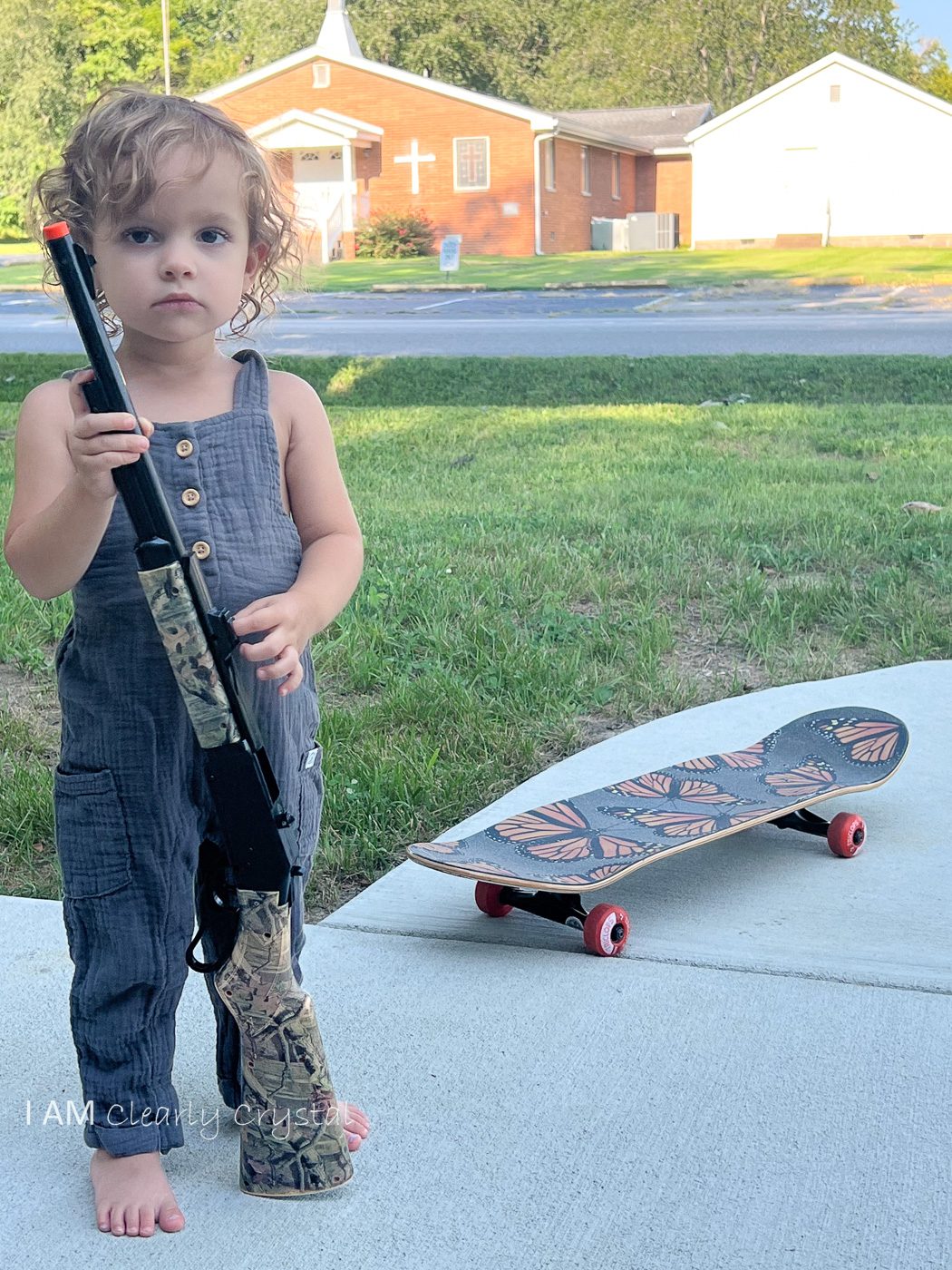 toddler with toy gun and skateboard